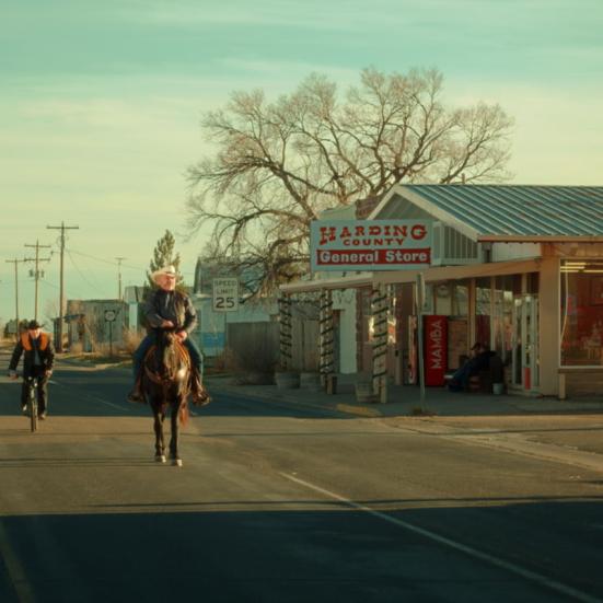 mand rider på hest gennem en lille amerikansk by